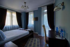 a bedroom with a bed and a desk and windows at Pulpudeva Family Hotel in Plovdiv +74 photos