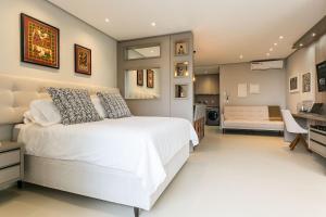 a bedroom with a white bed and a desk at Gym | Food Hall | 450m from the mall #CA04 in Florianópolis