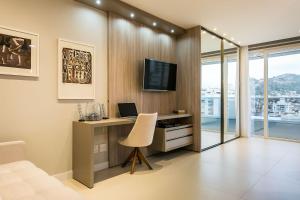a room with a desk with a computer and a television at Gym | Food Hall | 450m from the mall #CA04 in Florianópolis