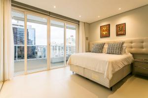 a bedroom with a bed and large windows at Gym | Food Hall | 450m from the mall #CA04 in Florianópolis +30 photos