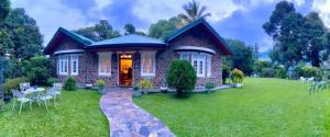 a brick house with a grassy yard with a table and chairs at Sithara Estate Bungalow in Ella