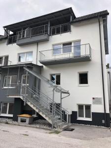 Un gran edificio blanco con escaleras y un banco al frente. en CityApartment MELITTA, en Schladming