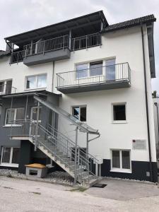 un gran edificio blanco con escaleras y un banco en la parte delantera en CityApartment MELITTA, en Schladming