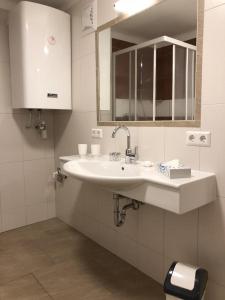 Un baño blanco con lavabo y espejo. en CityApartment MELITTA, en Schladming