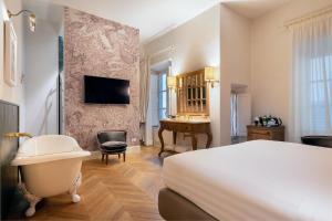um quarto de hotel com uma cama, uma banheira e uma secretária em Corte Calzaiuoli Elegant Suites em Florença