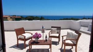 a patio with four chairs and a table with flowers at Hotel Resort Nuraghe Arvu in Cala Gonone