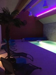 a room with a pool with a palm tree and purple lighting at Agathe et Titi in Marigny-lès-Reullée