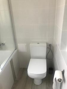 a white bathroom with a toilet and a shower at Apartamenty Jana in Katowice