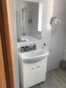 a white bathroom with a sink and a mirror at Apartamenty Jana in Katowice