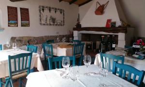 a restaurant with white tables and blue chairs and wine glasses at Hotel Resort Nuraghe Arvu in Cala Gonone