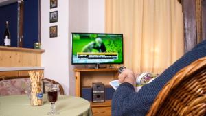 una persona sentada en una mesa viendo una televisión en Ferienwohnung KraftTanken en Hallstatt