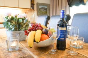 a bowl of fruit with a bottle of wine and glasses at Colthrop Manor with Gardens in Thatcham