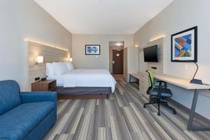 a hotel room with a bed and a desk and a couch at Holiday Inn Express & Suites - Grand Rapids Airport - South, an IHG Hotel in Grand Rapids