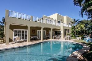 uma casa grande com uma piscina em frente em Caza Beach Guesthouse em Durban