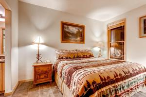 a bedroom with a bed and a night stand with two lamps at Corral at Breckenridge #103E - Private Hot Tub - Close to Town in Breckenridge