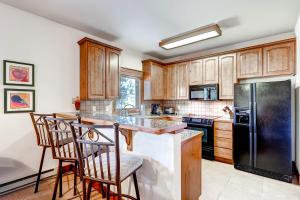 a kitchen with wooden cabinets and a black refrigerator at Saddlewood #46 Ski-In/Ski-Out to Snowflake Lift - Walk to Town in Breckenridge