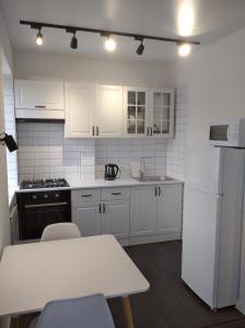 a kitchen with white appliances and a table and chairs at White Apartment in Poltava