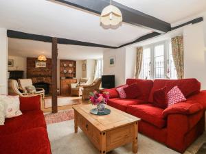 a living room with red couches and a coffee table at Church Farmhouse in Winsham