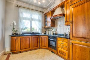 een keuken met houten kasten, een wastafel en een raam bij Willa Biały Dom in Rybnik
