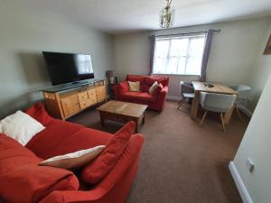 a living room with a red couch and a table at Entire 2 Bedroom Apartment free parking in Saffron Walden