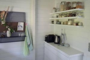 una cocina con paredes blancas y encimeras y estanterías blancas en Panoramic seaview from cottage, en Omø By