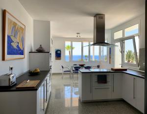 cocina con armarios blancos y vistas al océano en Villa Dois Mares Puerto Calero, en Puerto Calero