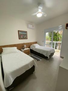 a bedroom with two beds and a ceiling fan at Apto Novo Duplex em Juqhey in Juquei +58 photos