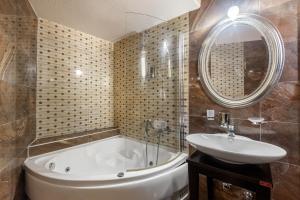 łazienka z wanną, umywalką i lustrem w obiekcie Toti Boutique Rooms w Kalambace