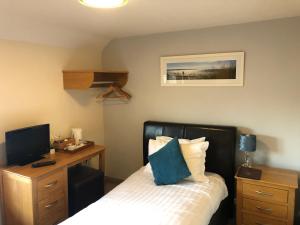 a bedroom with a bed and a desk with a computer at The Elm Tree Inn in Wisbech