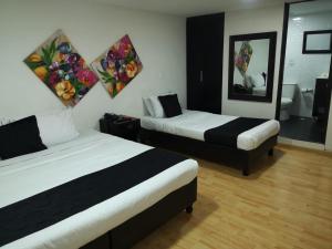 Cette chambre comprend 2 lits et un miroir. dans l'établissement Hotel Santiago Plaza, à Bogotá