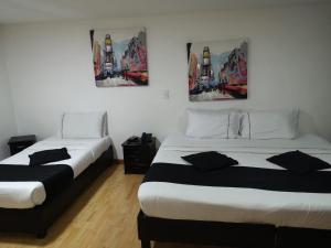 2 camas en una habitación con pinturas en la pared en Hotel Santiago Plaza, en Bogotá