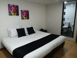 Cama blanca y negra en habitación con aseo en Hotel Santiago Plaza, en Bogotá