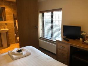 a bedroom with a bed and a television and a bathroom at The Elm Tree Inn in Wisbech