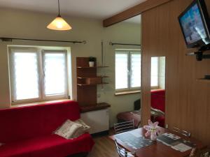 een woonkamer met een rode bank en een tafel bij APARTAMENTY-STUDIO noclegi wczasy wakacje ferie - pobyty rodzinne in Rabka