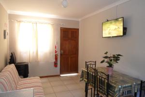 a living room with a table and a television on the wall at Sunrise Cottage in Upington