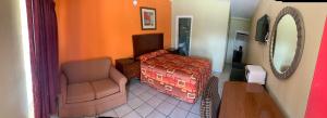 1 dormitorio con cama, silla y espejo en Budget Inn Greenville, en Greenville