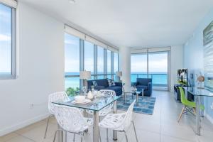 Global Luxury Suites at Monte Carlo في ميامي بيتش: غرفة معيشة مع طاولة وكراسي زجاجية