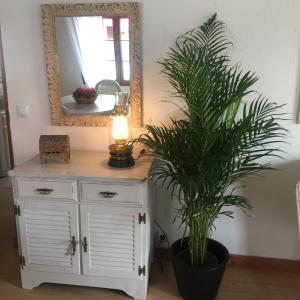 uma cómoda branca com um espelho e um vaso de plantas em El balcón de Araceli em Cercedilla