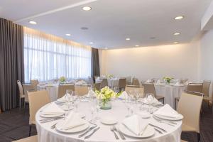 a conference room with tables and chairs with white table settings at NH Queretaro in Querétaro
