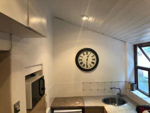 un reloj en la pared de una cocina con fregadero en Mole Cottage en Stocksfield