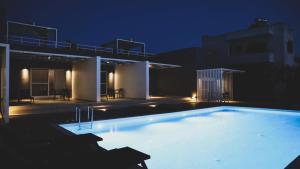 duży basen w nocy z budynkiem w obiekcie Galinio Boutique Apartments w mieście Skafidia