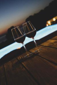 Galinio Boutique Apartments في سكافيديا: كأسين من النبيذ يجلسون على طاولة خشبية