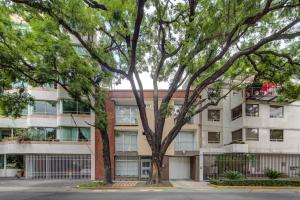 an apartment building with trees in front of it at Grupo Kings Suites - Horacio 1525 in Mexico City