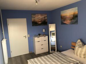 um quarto com paredes azuis e uma cama e um espelho em Ferienwohnung Aueblick Kassel em Kassel