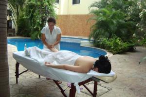 a woman sitting on a bed in front of a pool at Gran Real Yucatan in Mérida