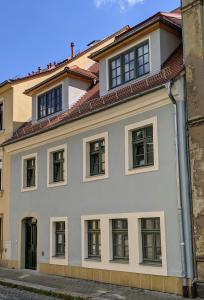 ein weißes Gebäude mit Fenstern auf einer Straße in der Unterkunft Gut schlafen in der Innenstadt von Zittau - Ferienwohnungen IO19 in Zittau