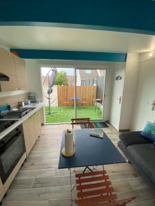 a living room with a table in front of a kitchen at Maisonnette de la mer in Hermanville-sur-Mer