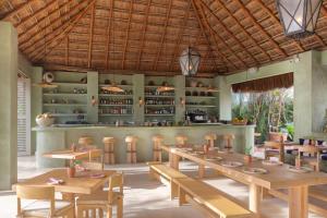 un restaurante con mesas de madera y un bar en Hotel Panamera en Tulum