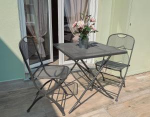 a black table with two chairs and a vase with flowers at WellHome Asti Premium Apartments with Private Terrace & Garden in Asti