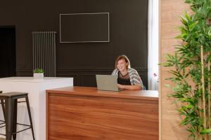 una mujer sentada en un escritorio con un ordenador portátil en THE City Lodge - Boutique Apartments, en Zagreb